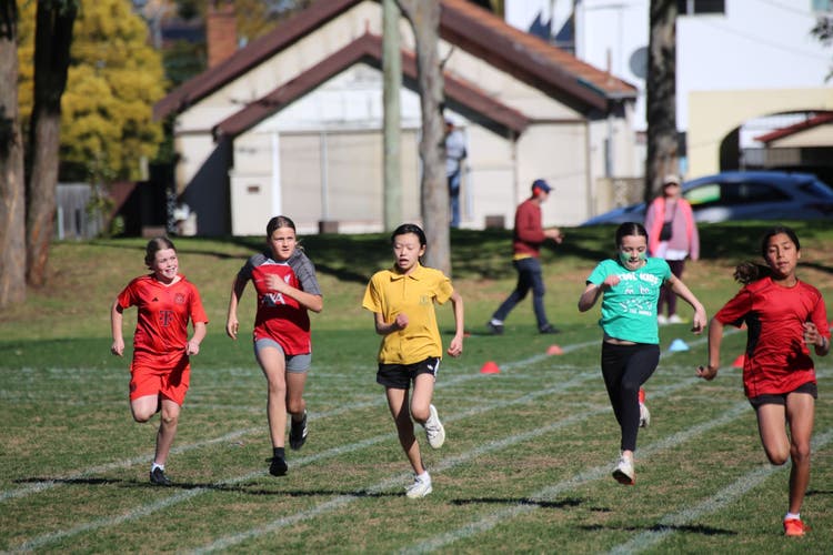 Photograph of five girls running in a race at an athletics carnival.