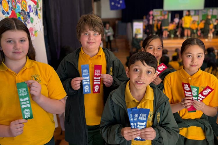 Photograph of students holding up their ribbons for sporting events.