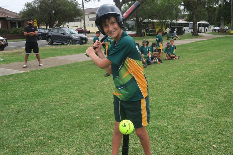 Photograph of a male student who is hitting a ball in T-ball.