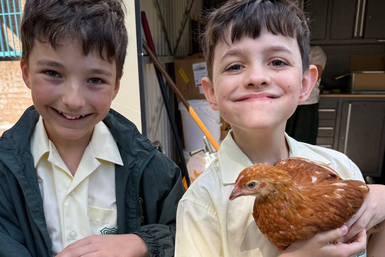Photograph of two male students holding chickens.