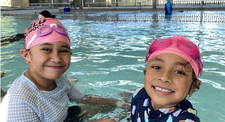 Photograph of two female students in a swimming pool.